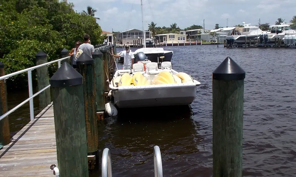 A tour boat tying up at the public dock at Goodland Boat Park, 750 Palm Point Dr, Goodland, Florida, with the village and its boat lifts across the channel